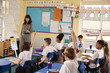 © Monkey Business - Primary school kids raising hands in class to answer teacher