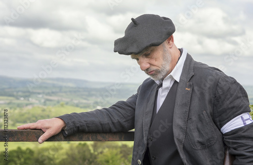 Poster Portrait image of a French Resistance soldier looking down to the floor, with green fields in the background