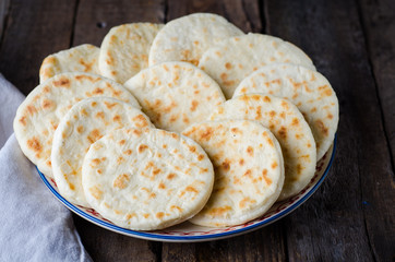 Freshly baked Moroccan mini flatbread - batbouts on wooden table. Selective focus. Arabian food