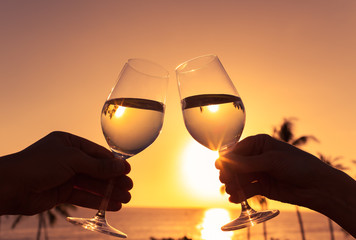 Wall Mural - Cheers to a beautiful life! Pair of wine glasses toasting against a beautiful sunset. 