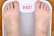 © zdravinjo - Barefoot person standing on the weight scale. The scale shows FAT!
