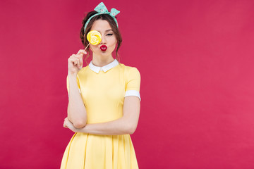 Poster - Funny lovely pinup girl covered one eye with yellow lollipop