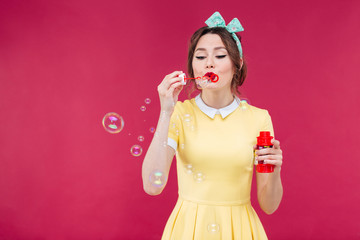 Sticker - Cute lovely young woman in yellow dress blowing soap bubbles