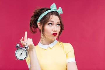 Poster - Unhappy pretty young woman holding alarm clock