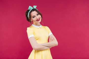 Canvas Print - Smiling young woman in yellow dress standing with arms crossed