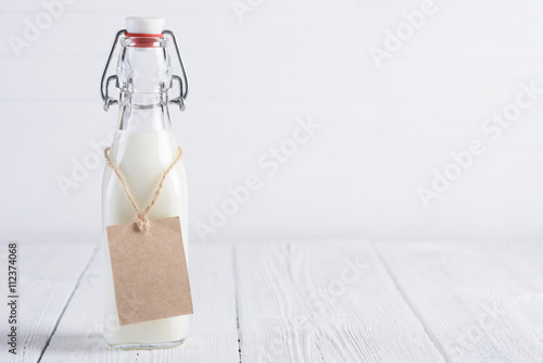 Zdjęcie XXL Butelka mleko z pustego papieru etykietką na arkanie na bielu malował drewnianego stołu wciąż życie