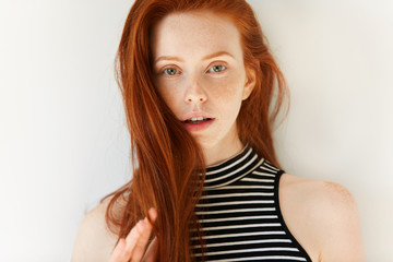 Close up portrait of beautiful sensual Caucasian young female with long loose red hair and perfect freckled skin looking at the camera with parted lips showing white teeth. Youth and beauty concept