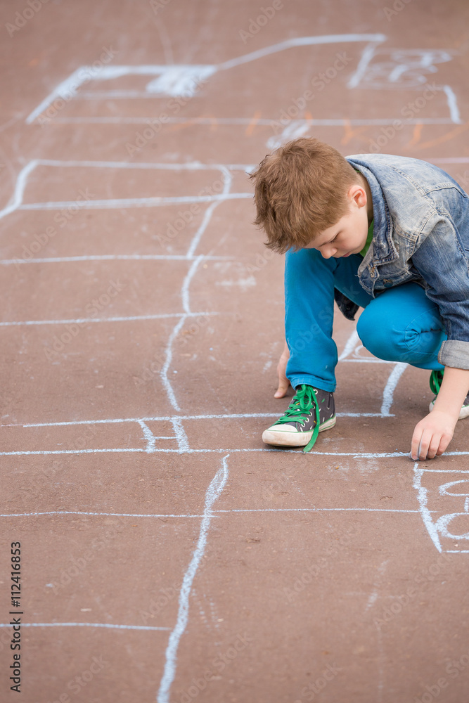 Cute kid boy drawing with chalk on the pavement in the park. Summer ...