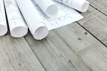 rolls of architectural blueprints and plans on gray wooden board