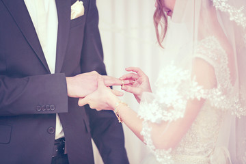 Wall Mural - Bride putting a ring on groom's finger