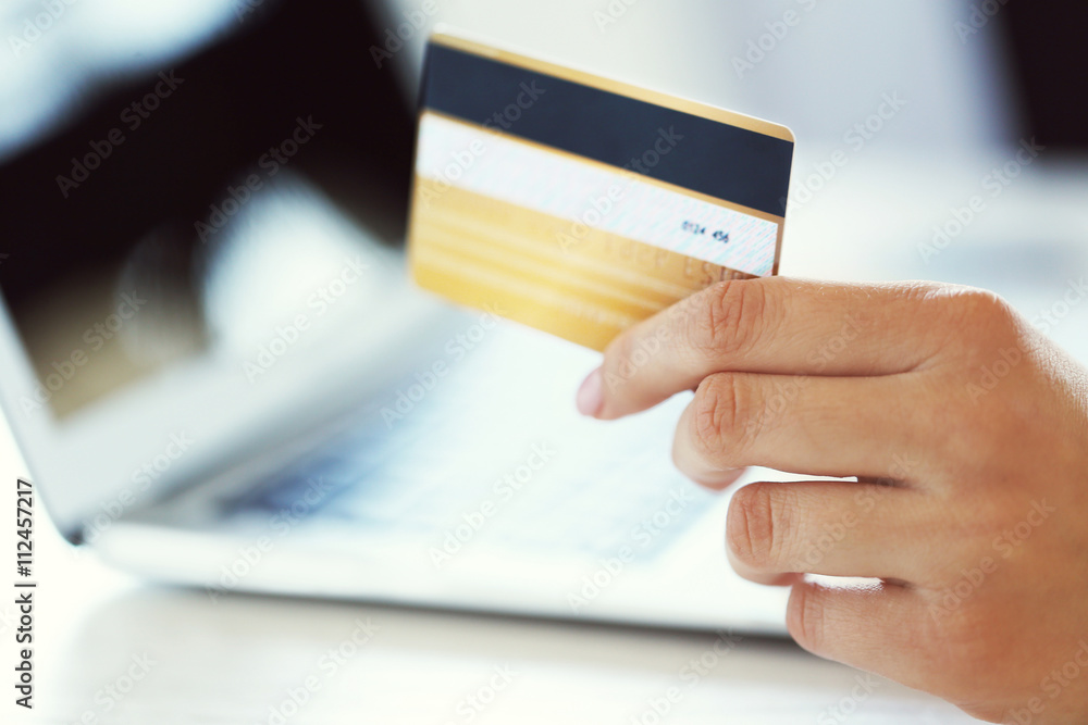 Hand holding plastic credit card and using laptop. Online shopping concept.