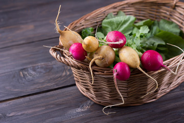 Wall Mural - Fresh radishes in a wicker basket on a wooden background 