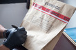 hand in glove writing on evidence bag and seal by red tape 