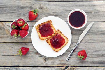 French toasts with jam and strawberry on wooden table