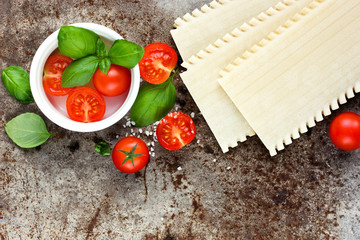 Wall Mural - Lasagna pasta, cherry tomatoes and basil on old metal background