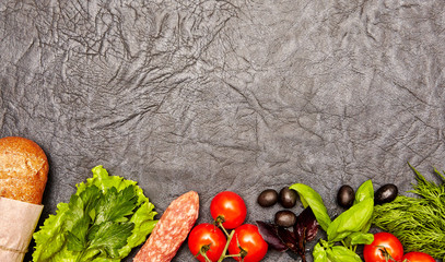 Ingredients for sandwich with salami, bread, herbs, olives, tomatoes and spices on dark background. Top view