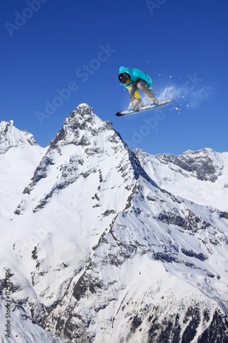 Cuadros en Lienzo Corredor de snowboard que salta sobre las montañas