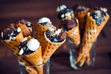 Tasty chocolate ice cream in waffle cone on brown wooden backgro