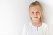 © WHstudio Leushin N - Blond Caucasian female child with green eyes standing quietly indoors and looking straight forward in good and sunny day. White colors make little girl look like a little angel or innocent baby.