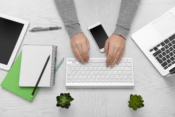 Wall Mural - Woman hands at table with computer, tablet, smart phone and other things, top view