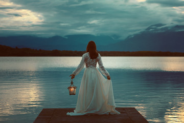 Woman waiting with lantern on a pier