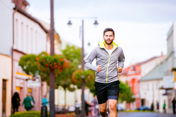 Young hipster man running in town, main street