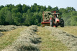 Freshly Baled Hay – A tractor pulls a hay baler and wagon, gathering the tedded windrows.