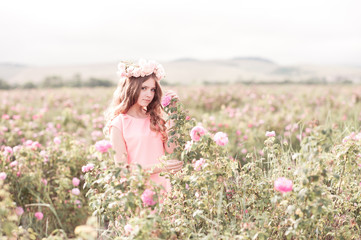 Beautiful teen girl 14-16 year old posing in rose field. Wearing wreath with flowers. Teenager hood.