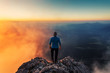 © Lukas Furlan - Rear view of man on top of cloudy rocky mountain in sunlight
