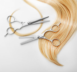 Wall Mural - Hairdresser's scissors with strand of blonde hair, isolated on white