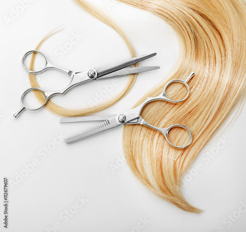 Foto Hairdresser's scissors with strand of blonde hair, isolated on white