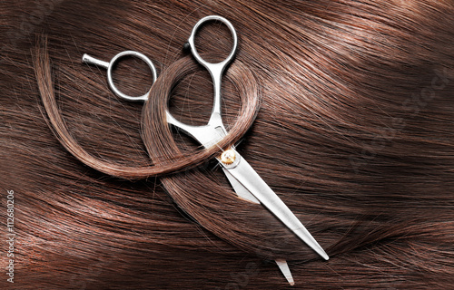 Leinwand Poster Hairdresser's scissors with dark brown hair, close up
