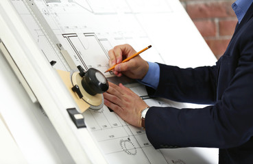 Engineer working with blueprint on panel board indoors