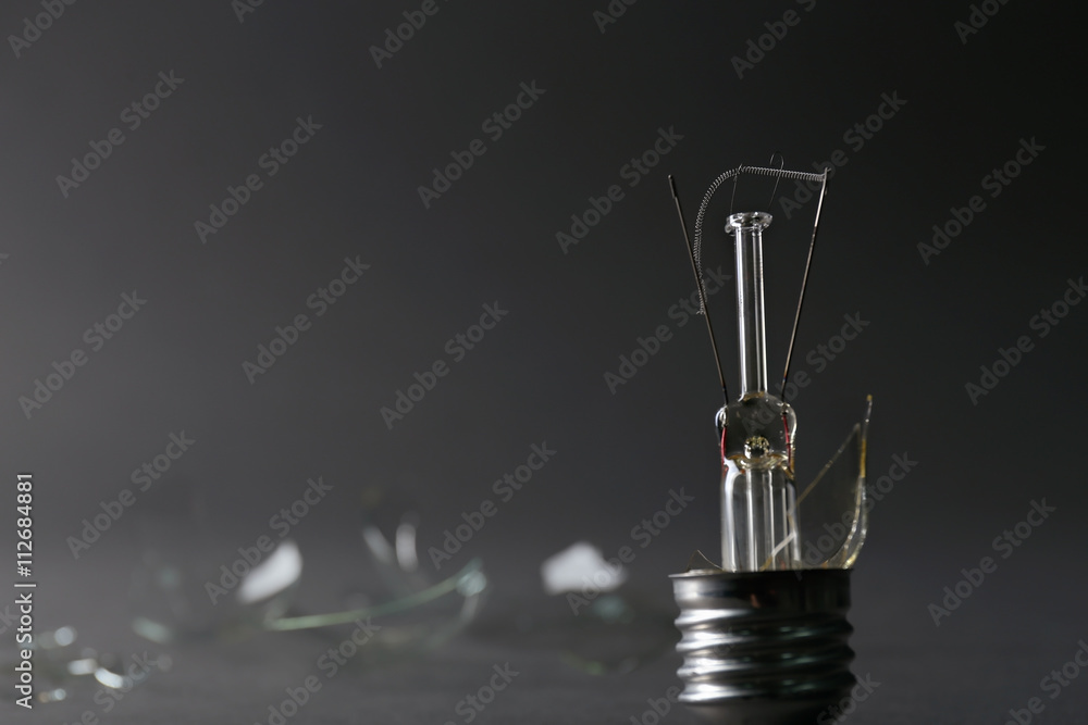 Broken light bulb on grey background