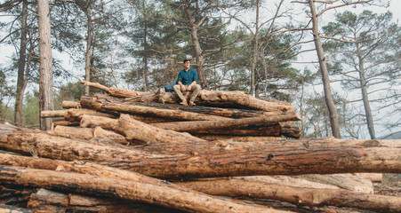 Poster - Tourist resting on stack of woods