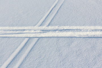 Two ski tracks which are crossed on snow in winter day