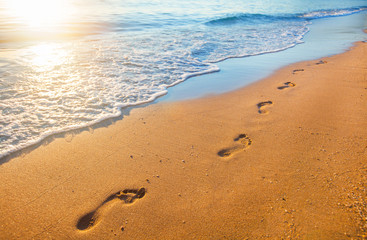 Wall Mural - beach, wave and footprints at sunset time