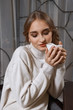 © boomeart - pretty girl in sweater and socks sitting behind the table wit cup