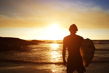 Male Surfer Watching The Sunset At The Beach