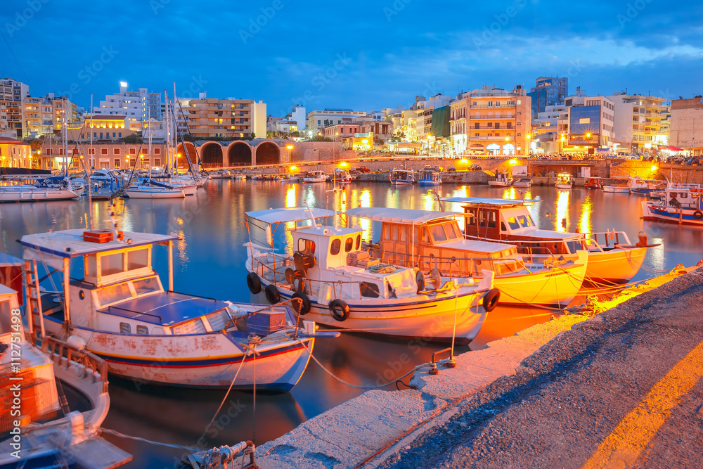 Obraz na płótnie Old harbour of Heraklion with fishing boats and marina during twilight blue hour, Crete, Greece. Boats blurred motion on the foreground. w salonie