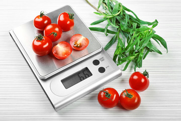 Wall Mural - Tomatoes with digital kitchen scales on wooden background