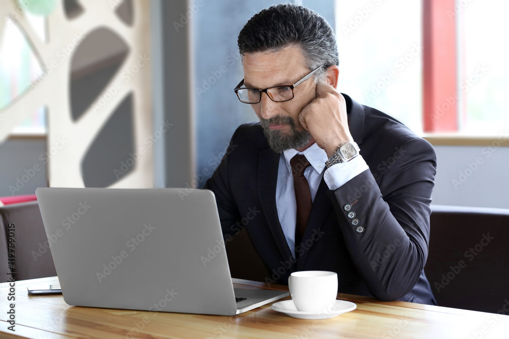 Businessman with laptop in cafe