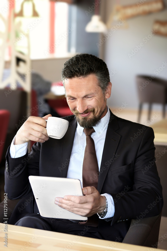 Businessman with coffee and tablet in cafe