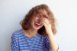 Fototapeta  - Laughing woman with curly hair on white wall