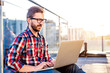 © Halfpoint - Businessman working from home on laptop, sitting on balcony