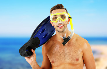 Canvas Print - Young man with swimming mask or goggles with flippers on blurred sea background