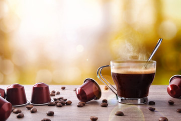 Cup of coffee with capsules and bainas and local background