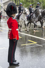 Guard Stands At Attention As A Horse-drawn Procession Carrying Queen Elizabeth II Toward Buckingham Palace Passes Along A Rainy Street In London, UK