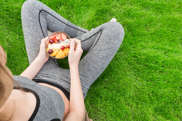 Young girl eating a fruit salad after a workout . Fitness and healthy lifestyle concept.