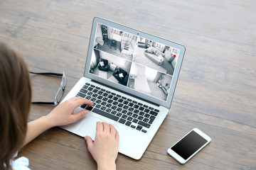 Woman using laptop at the table. Home security system concept